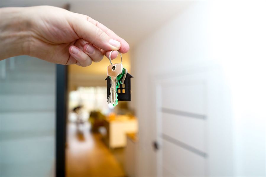 Hand holding house keys on a house-shaped keychain