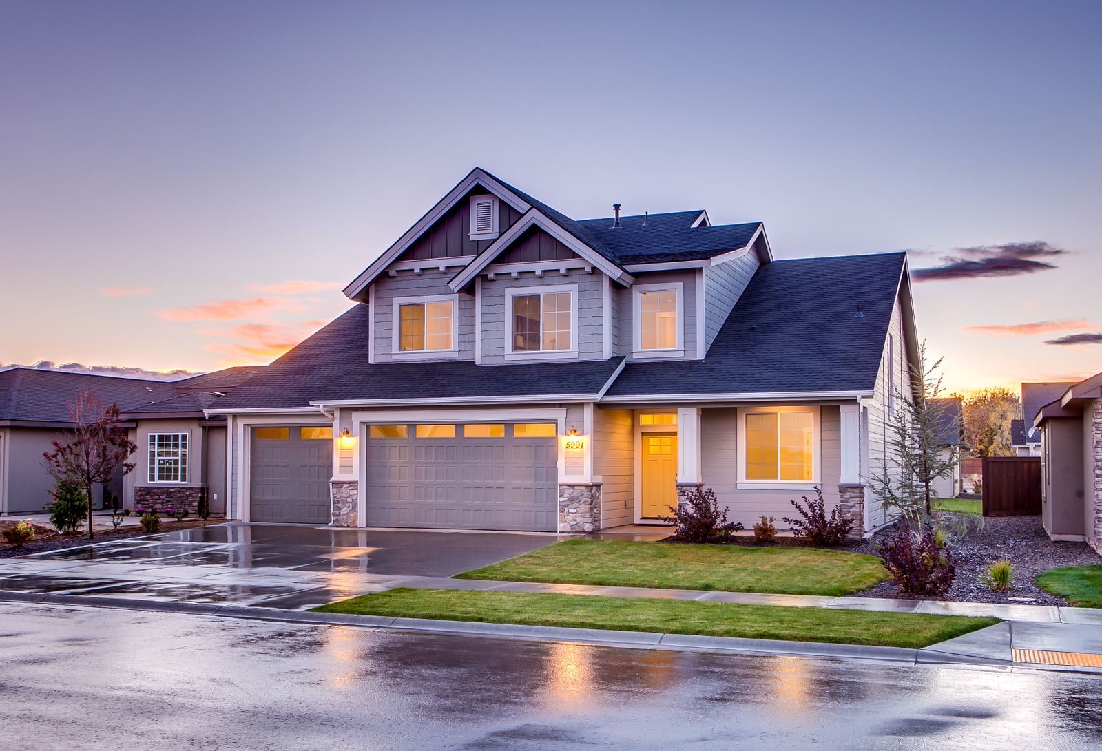Two-story suburban house with a lit porch and double garage at dusk, the kind of home people learn to sell on their own